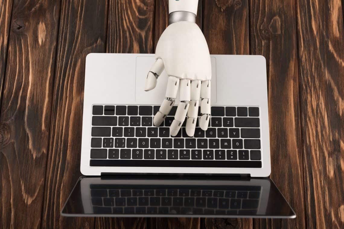 A robot's hand typing on a computer, symbolic of artificial intelligence for blogging.